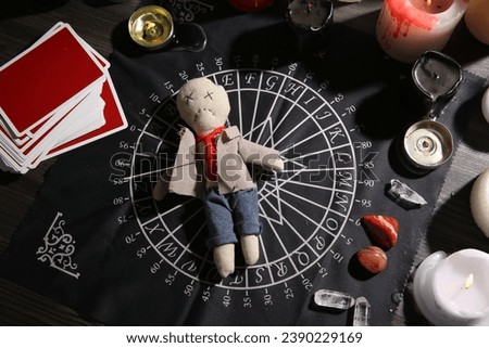 Voodoo doll pierced with needle surrounded by ceremonial items on table, flat lay. Curse ceremony