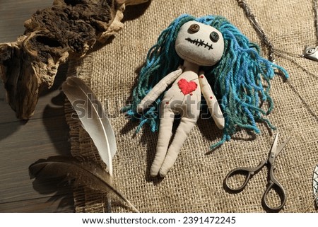 Voodoo doll with pins surrounded by ceremonial items on wooden table