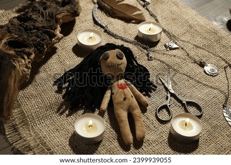 Voodoo doll with pins surrounded by ceremonial items on burlap fabric