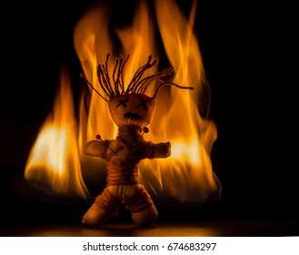 A voodoo doll stands in front of a fire