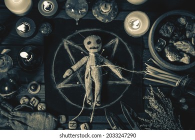 Voodoo Magic concept. Voodoo doll studded with needles with pierced rag heart on pentagram and around burning candles. Spooky or eerie magical esoteric ritual, black and white photo