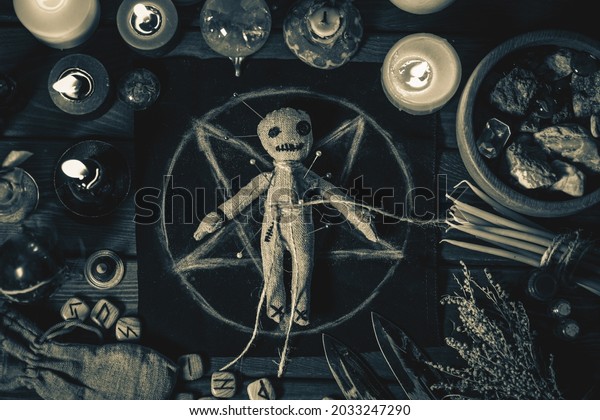 Voodoo\
Magic concept. Voodoo doll studded with needles with pierced rag\
heart on pentagram and around burning candles. Spooky or eerie\
magical esoteric ritual, black and white\
photo