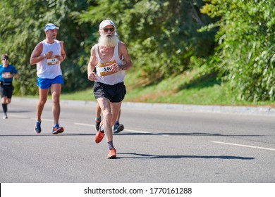 Voronezh, Russia - 24.08.2019 - Old Man Runs Along Road. Runners Marathon And Championship Competition, Copy Space. Street Sprinting Outdoors. Healthy Sport Event.