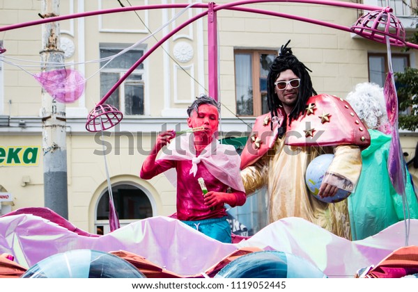 Voronezh, Russia, June 2018: Parade of street\
theaters, a boy with red skin and a man with dreadlocks riding on a\
bright unusual car.  Blowing\
bubbles.