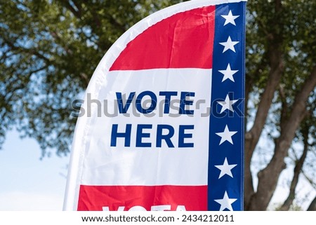 Vote Here high resolution text on political vote flag banner with fiberglass poles, polyester double-sided election decorations for polling locations on rotating pole, non-English-proficient, TX. USA