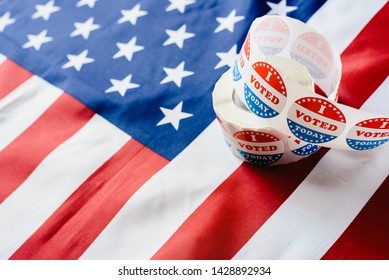 I vote today stickers roll, in US elections on American flag. - Shutterstock ID 1428892934
