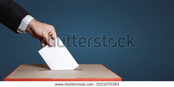 Voter Holds Envelope In Hand\
Above Vote Ballot On Blue Background. Freedom Democracy\
Concept