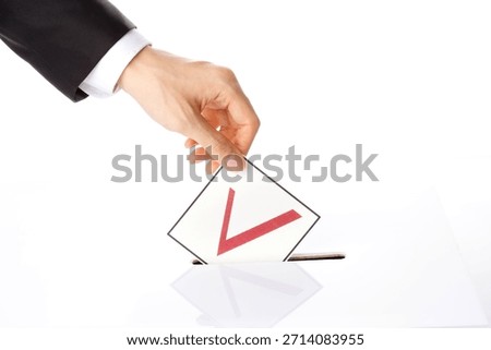 Voting process shows a hand placing a ballot in a box during an election event in a bright and open environment