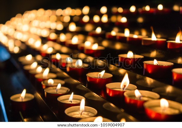 Votive prayer candles inside a catholic church on a\
candle rack
