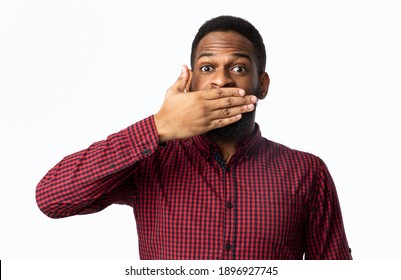 Vow Of Silence. Shocked African American Man Covering Mouth With Hand Looking At Camera Posing Standing Over White Studio Background. Not A Word, Mute Speechless Black Guy's Portrait