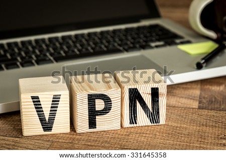 VPN (Virtual Private Network) written on a wooden cube in front of a laptop