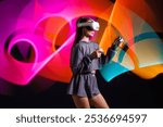 VR, AR, MR, XR Future technologies. Neon. Young girl in VR glasses in neon doing sports and playing a game. Concept of modern gadgets and technologies