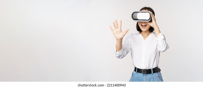 Vr chat. Asian girl saying hello in virtual reality glasses, smiling enthusiastic, concept of communication and future technology, white background