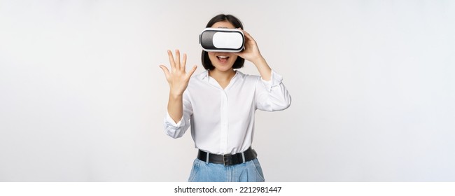 Vr chat. Asian girl saying hello in virtual reality glasses, smiling enthusiastic, concept of communication and future technology, white background