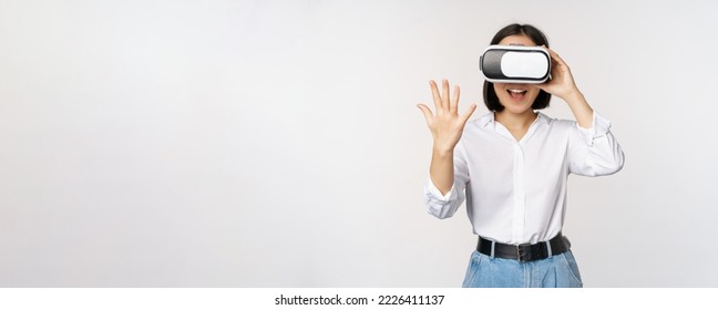 Vr chat. Asian girl saying hello in virtual reality glasses, smiling enthusiastic, concept of communication and future technology, white background.