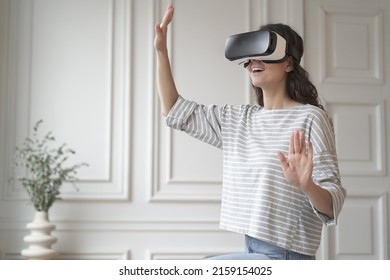 VR In ECommerce. Young Happy Woman In Casual Clothes Standing Indoors In Virtual Reality Headset And Enjoying Fun Shopping Experience In Augmented World, Touching Objects With Hands