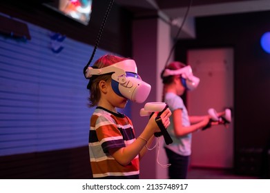 Vr Game And Virtual Reality. Team Kids Friends Gamers Fun Playing On Futuristic Simulation Video Game In 3d Glasses And Joysticks In Entertainment Vr Room With Innovation Technology And Neon Light