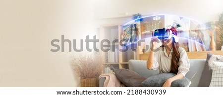 VR technology and entertainment at home concept.Young Asian Women Using Virtual Reality Headset(VR) for Online entertainment and choice movie in multimedia streaming application on Internet broadband