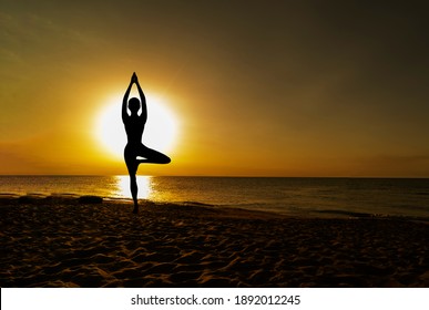 Vrikshasana tree pose from yoga by woman silhouette on sunset - Powered by Shutterstock