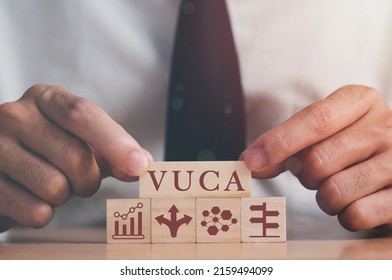 VUCA And Strategic Management. Hand Puts Wooden Cubes With VUCA Icon And Text Volatility, Uncertainty, Complexity, Ambiguity With Grey Background. Smart Management For New Trend And Rapid Transition. 