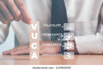 VUCA And Strategic Management. Hand Puts Wooden Cubes With VUCA Icon And Text Volatility, Uncertainty, Complexity, Ambiguity With Grey Background. Smart Management For New Trend And Rapid Transition. 