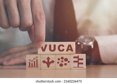 VUCA And Strategic Management. Hand Puts Wooden Cubes With VUCA Icon And Text Volatility, Uncertainty, Complexity, Ambiguity With Grey Background. Smart Management For New Trend And Rapid Transition. 