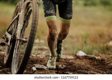 V.Ufaley, Russia - August 12, 2018: Dirty Bike And Legs Mountain Biker Uphill Walk During Race XCM Big Stone