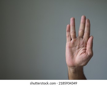 Vulcan Hand Gesture Against A Plain Background.