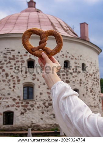Vyborg pretzel in hand against the background of the old round tower (Symbol of Vyborg)