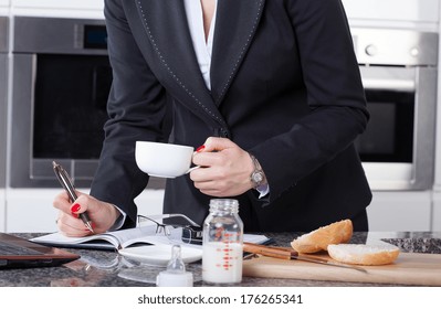 W businesswoman drinking coffee, working and making a meal for her kids