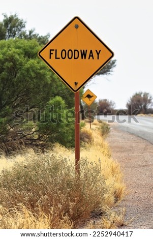 W-5-7-1 road sign: black FLOODWAY word on diamond-shaped yellow background reminds drivers that they about to cross a floodplain-shallow depression that is subject to flooding. Petermann-NT-Australia.