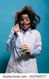 Wacky Chemist With Pipette And Chemistry Flask Mixing Chemical Compounds To Create Experimental Serum. Crazy Mad Scientist Using Pipette To Drip Compound Inside Beaker Filled With Liquid Substance.