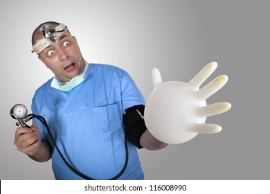 Wacky Doctor Measure His High Blood Pressure. Funny Young Man In Doctor Close With Blood Pressure Gauge In His Hand And Inflate His Surgeon Glove