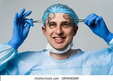 Wacky Smiling Doctor Surgeon With Crazy Emotions. Young Doctor Holding Medical Scissors