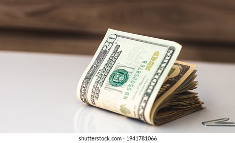 A wad of folded American dollars money isolated on white surface. The new hundred-dollar bill is on top of the other banknotes.
