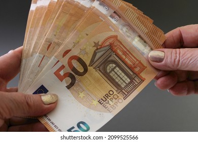 Wad of money of 50 euro banknotes in female hands, isolated on a grey background. Woman holding euro money. Close up view.