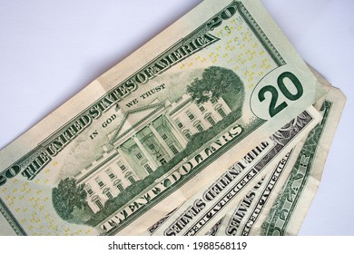 Wad of US dollar bills piled up and partially spread out on a white background.