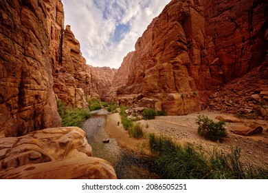 Wadi Mujib Biosphere Reserve, red rock ravine gorge with river. Jordan water stream with blue sky. Wadi Mujib lowest nature reserve landscape, with a spectacular array of scenery near Dead Sea.