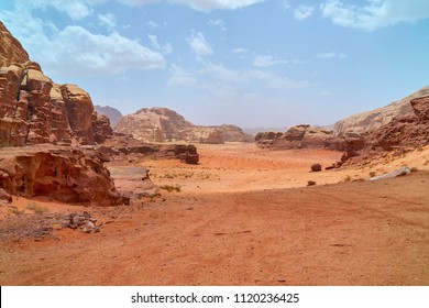 Wadi Rum desert, Jordan, The Valley of the Moon. Orange sand, haze, clouds. Designation as a UNESCO World Heritage Site. Red planet Mars  landscape. Offroad adventures travel background.               - Powered by Shutterstock