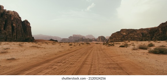 Wadi Rum desert, Jordan, The Valley of the Moon. Orange sand, haze, clouds. Designation as a UNESCO World Heritage Site. National park outdoors landscape. Offroad adventures travel background.
