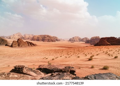 Wadi Rum desert, Jordan,  The Valley of the Moon. Orange sand, haze, clouds. Designation as a UNESCO World Heritage Site. National park outdoors landscape. Offroad adventures travel background.        - Shutterstock ID 2177548139