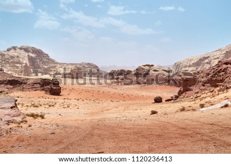    Wadi Rum desert, Jordan,  The Valley of the Moon. Orange sand, haze, clouds. Designation as a UNESCO World Heritage Site. National park outdoors landscape. Offroad adventures travel background.    