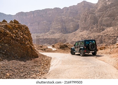 Wadi Tiwi, Oman - 04.05.2018: Black Jeep  Wrangler By The Side Of A Narrow Asphalt Road In A Hot Dry Gorge Of Wadi Tiwi, Oman. Travelling In Arabia. Super Hot Sunny Day With Heat Haze.