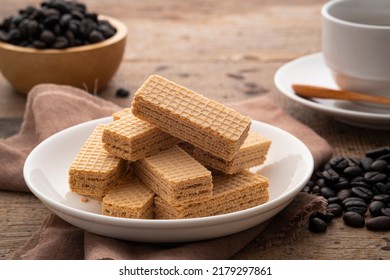 Wafer with coffee flavored cream in white plate with cup and coffee bean background