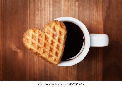 Waffle biscuits in shape of heart with cup of coffee on wooden background for Valentines day, top view - Powered by Shutterstock