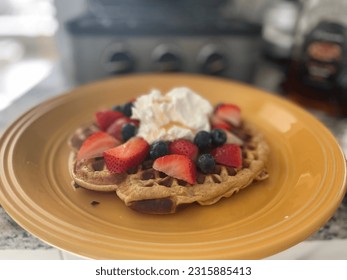 Waffle with blackberries, strawberries and whippedcream on top served in a yellow plate