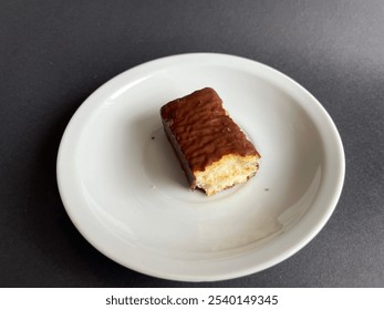 Waffle chocolate bar bitten on small white plate isolated on black background - Powered by Shutterstock