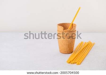 Waffle coffee cups and pasta straws on neutral background with copy space. Zero waste, plastic free, stop pollution, ecological concept