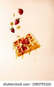 waffle flying with strawberries, bananas and maple, cream background 