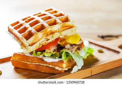 Waffle sandwich with meat, cheese, sauce and vegetables on wooden table background